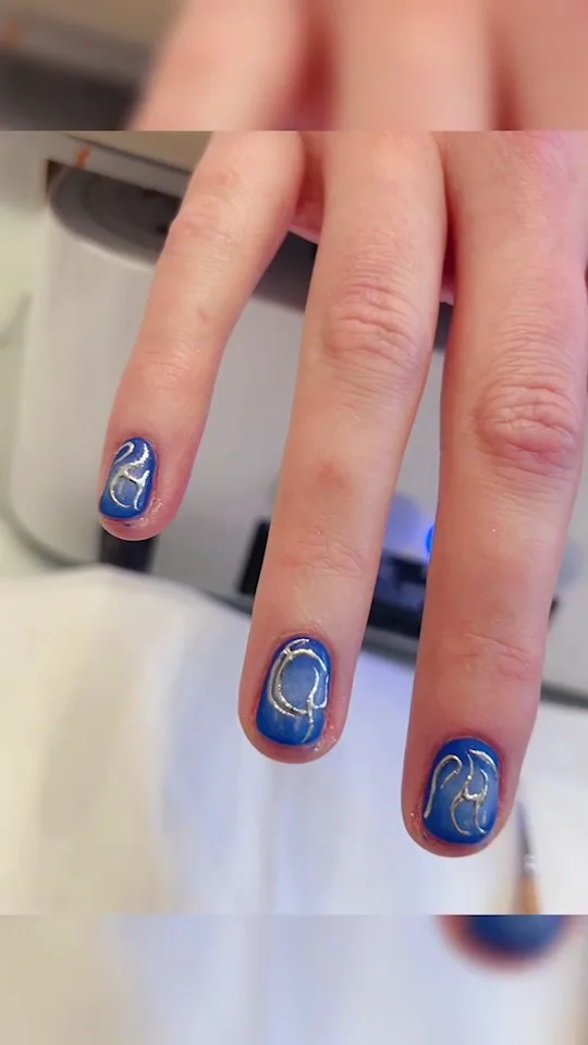 Short cobalt-blue nails with silver swirl line-work